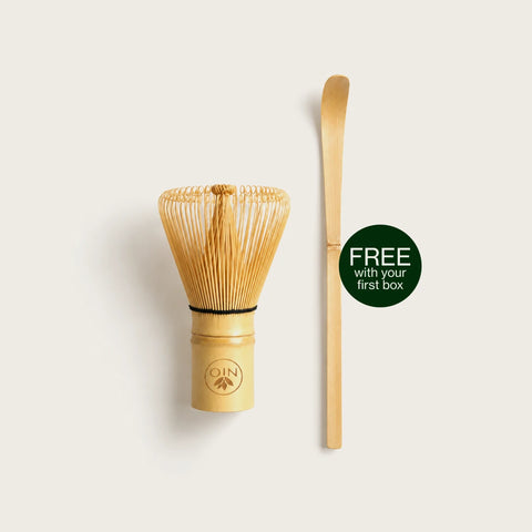 A bamboo whisk and bamboo scoop set displayed on a light beige background, featuring a dark green circular badge that reads 'FREE with your first box'. The brand logo 'ON' is visible on the base of the whisk.
