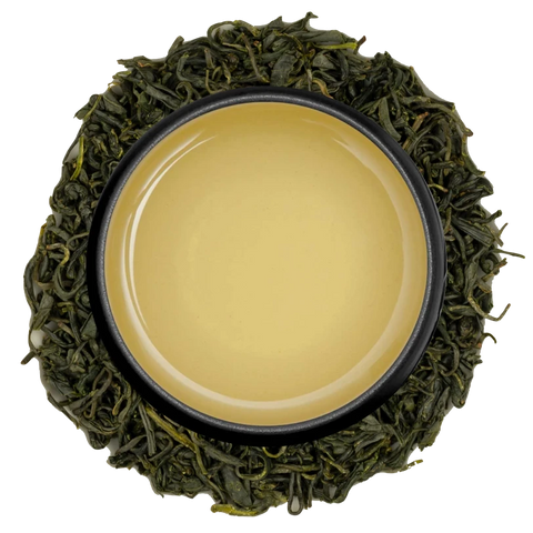 A cup of pale golden Japanese oolong seen from above, ringed by partly oxidised oolong leaves on a white background